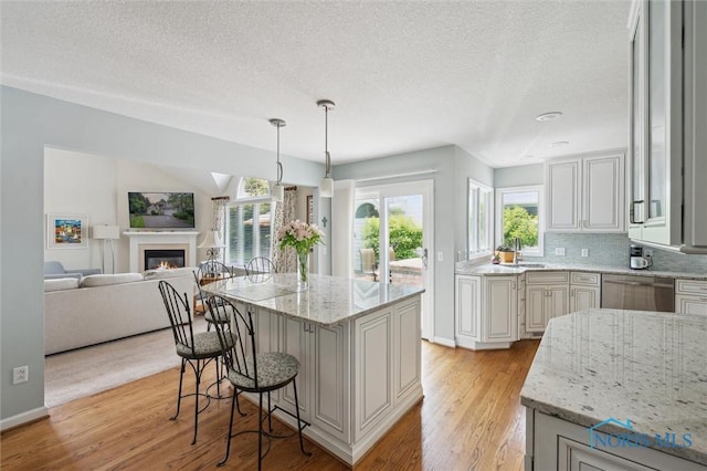 7445 Country Commons Ln Unit 7445, Sylvania, OH 43560 - kitchen featuring dishwasher, light wood-style flooring, a breakfast bar, a textured ceiling, and open floor plan