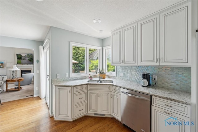 7445 Country Commons Ln Unit 7445, Sylvania, OH 43560 - kitchen with stainless steel dishwasher, light wood finished floors, backsplash, light stone countertops, and a textured ceiling