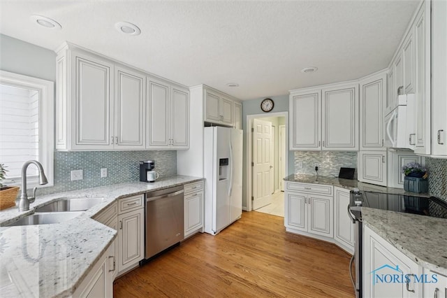 7445 Country Commons Ln Unit 7445, Sylvania, OH 43560 - kitchen featuring stainless steel appliances, decorative backsplash, light wood finished floors, light stone countertops, and recessed lighting