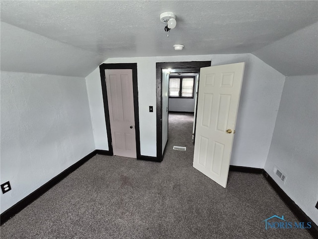 1133 Sherman St, Toledo, OH 43608 - additional living space with vaulted ceiling, dark carpet, and a textured ceiling