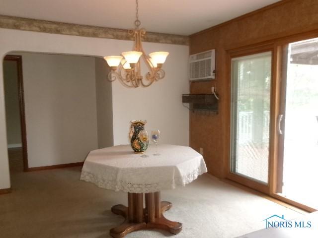 8962 State Route 109, Ottawa, OH 45875 - carpeted dining room with a chandelier, arched walkways, and a wall unit AC