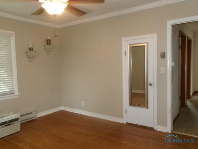 8962 State Route 109, Ottawa, OH 45875 - unfurnished room with ceiling fan, wood finished floors, crown molding, and a baseboard heating unit