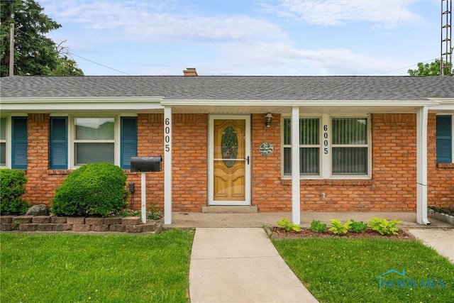 6005 Bahiamar Rd, Toledo, OH 43611 - view of exterior entry featuring a porch, brick siding, and a yard