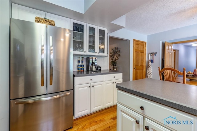 5868 Winslow Rd, Whitehouse, OH 43571 - kitchen with freestanding refrigerator, dark countertops, light wood-style floors, glass insert cabinets, and backsplash