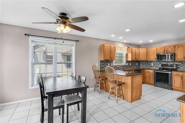 740 Tarra Oaks Dr, Findlay, OH 45840 - kitchen with stainless steel appliances, a peninsula, dark countertops, decorative backsplash, and a kitchen bar