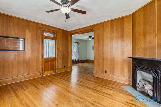 118 Allen Ave, Findlay, OH 45840 - unfurnished living room with ceiling fan, light wood-style floors, wood walls, and a fireplace with flush hearth