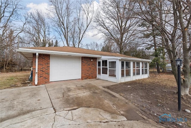922 Park St, Napoleon, OH 43545 - view of front of property with a sunroom, concrete driveway, brick siding, and an attached garage