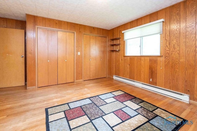 1527 Lockwood Rd, Findlay, OH 45840 - unfurnished bedroom with a baseboard radiator, two closets, wood finished floors, and wooden walls