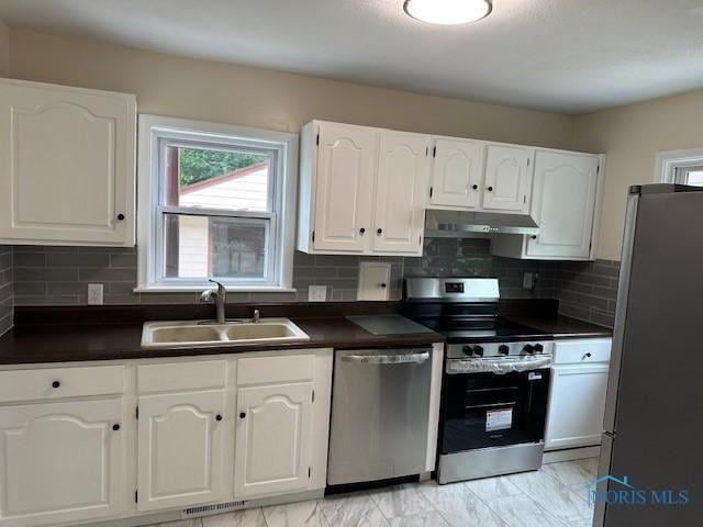 3748 Orono Dr, Toledo, OH 43614 - kitchen with appliances with stainless steel finishes, dark countertops, healthy amount of natural light, and light marble finish floors