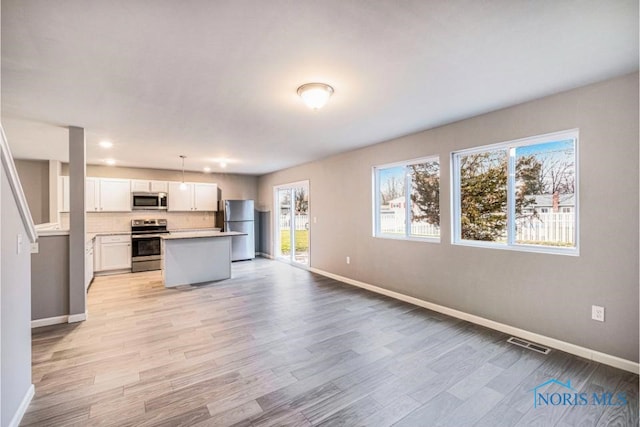 1113 Clairmont Ave, Napoleon, OH 43545 - kitchen with stainless steel appliances, open floor plan, a center island, white cabinetry, and light countertops