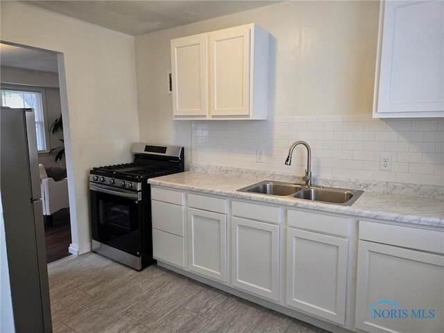 2421 106th Rd, Toledo, OH 43611 - kitchen with gas stove, freestanding refrigerator, light wood-type flooring, backsplash, and white cabinetry