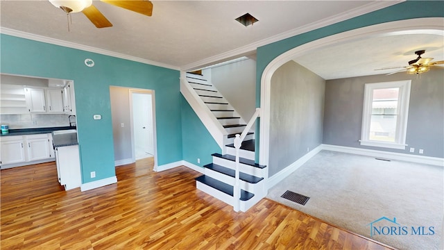 628 W Maple St, Clyde, OH 43410 - unfurnished living room with ceiling fan, arched walkways, light wood-style floors, ornamental molding, and stairway