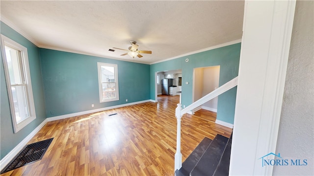 628 W Maple St, Clyde, OH 43410 - empty room with healthy amount of natural light, a ceiling fan, wood finished floors, crown molding, and a textured ceiling