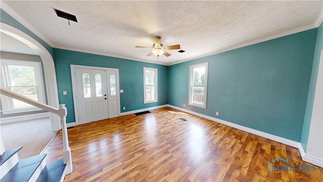 628 W Maple St, Clyde, OH 43410 - entrance foyer featuring wood finished floors, a textured ceiling, ceiling fan, ornamental molding, and arched walkways