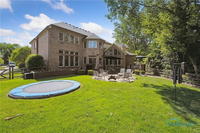 4811 Yosemite Pkwy, Sylvania, OH 43560 - rear view of house featuring a trampoline, brick siding, an outdoor fire pit, and a patio area