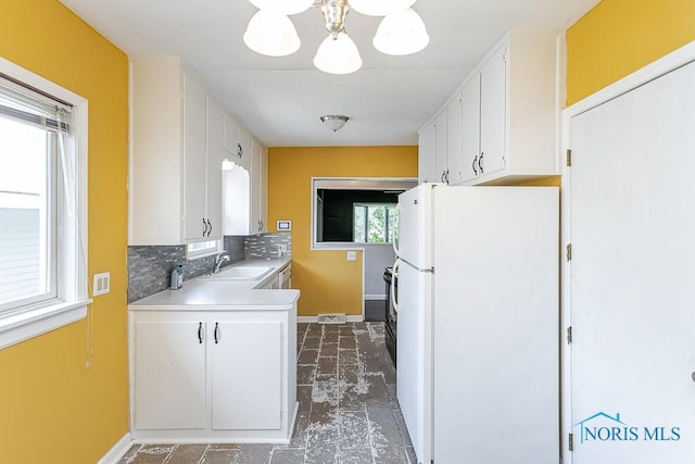 1040 Richland St, Maumee, OH 43537 - kitchen featuring freestanding refrigerator, a chandelier, white cabinetry, light countertops, and backsplash