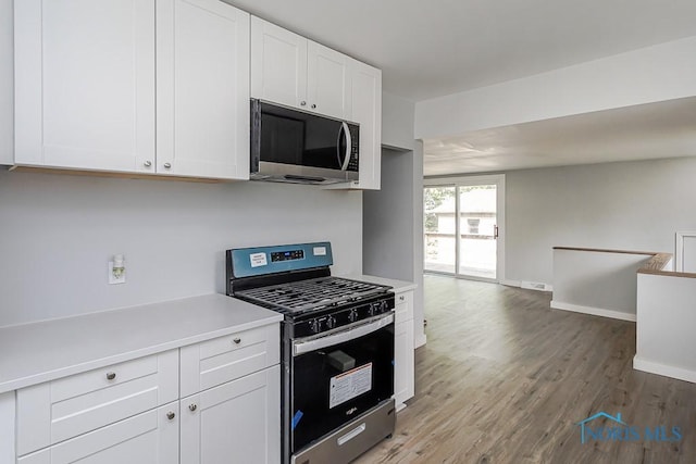 1302 Laning Rd, Toledo, OH 43615 - kitchen with appliances with stainless steel finishes, light countertops, open floor plan, white cabinets, and wood finished floors