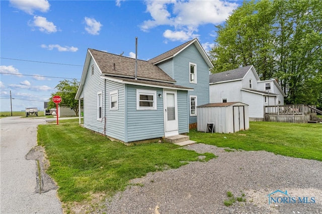 22856 Main St, Custar, OH 43511 - back of property featuring a storage unit, entry steps, roof with shingles, and a lawn