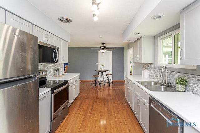 2941 Seaman Rd, Oregon, OH 43616 - kitchen featuring appliances with stainless steel finishes, light countertops, ceiling fan, decorative backsplash, and light wood-type flooring