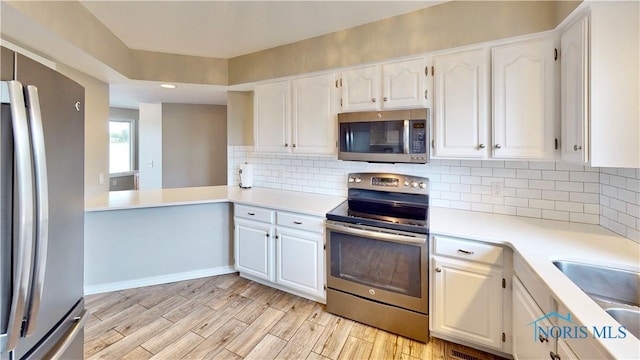 2109 Ottawa River Rd Unit 3C, Toledo, OH 43611 - kitchen with appliances with stainless steel finishes, white cabinetry, light countertops, decorative backsplash, and light wood-type flooring