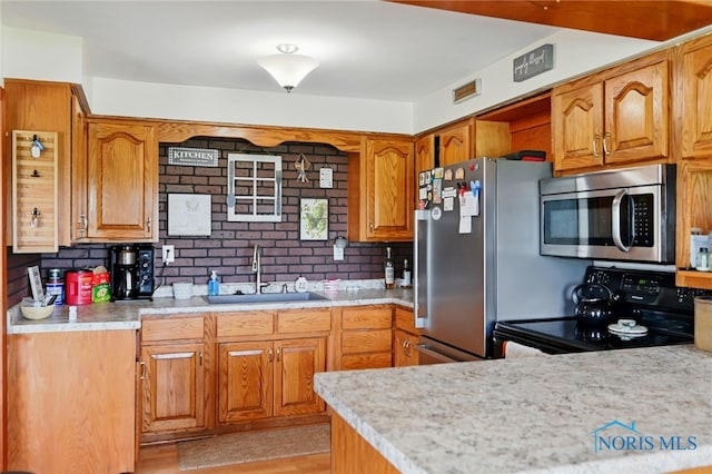 12505 Bloomlock Rd, Delphos, OH 45833 - kitchen featuring appliances with stainless steel finishes, brown cabinetry, and light wood-style flooring