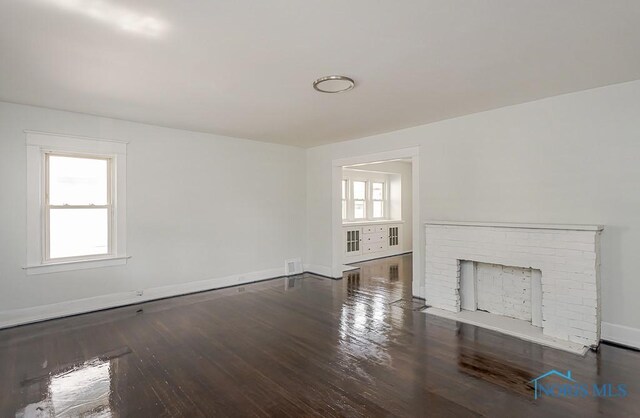 1385 Berdan Ave, Toledo, OH 43612 - unfurnished living room with healthy amount of natural light, wood finished floors, and a brick fireplace