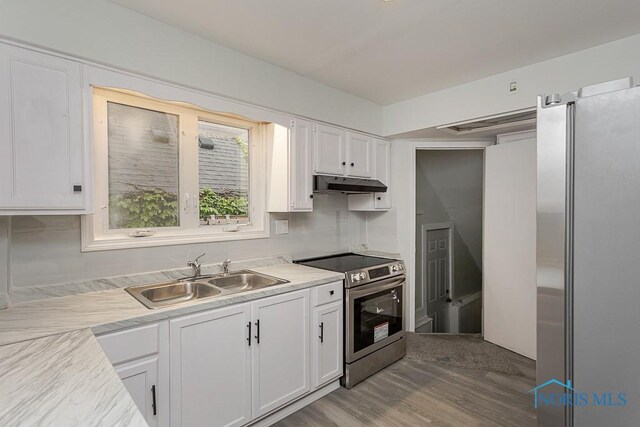 1385 Berdan Ave, Toledo, OH 43612 - kitchen featuring appliances with stainless steel finishes, under cabinet range hood, white cabinetry, wood finished floors, and light countertops