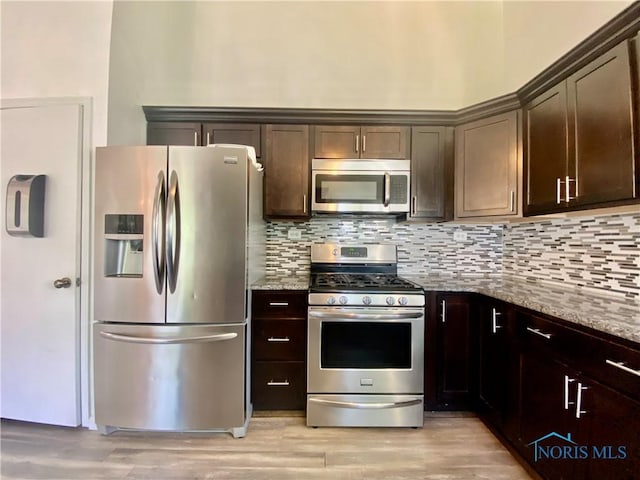 3800 Harrowsfield Rd, Sylvania, OH 43560 - kitchen with stainless steel appliances, light stone countertops, dark brown cabinetry, decorative backsplash, and light wood finished floors