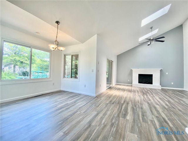 3800 Harrowsfield Rd, Sylvania, OH 43560 - unfurnished living room with lofted ceiling, wood finished floors, a chandelier, a brick fireplace, and a skylight