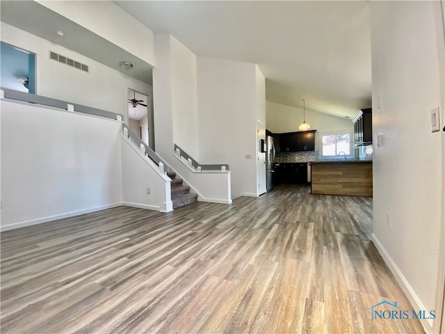 3800 Harrowsfield Rd, Sylvania, OH 43560 - unfurnished living room featuring wood finished floors, lofted ceiling, a ceiling fan, and stairway