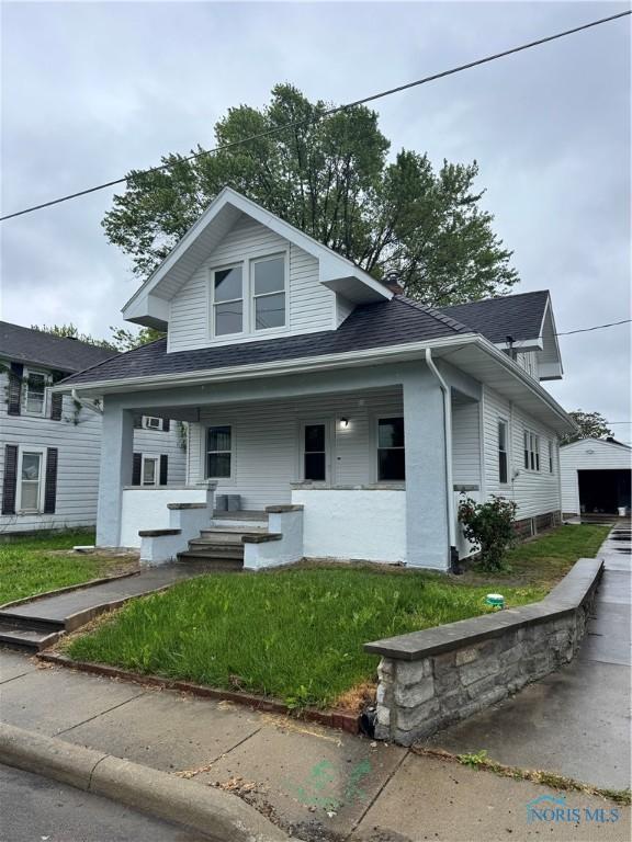 211 Garfield Ave, Findlay, OH 45840 - bungalow-style house featuring covered porch, roof with shingles, a front lawn, and a detached garage