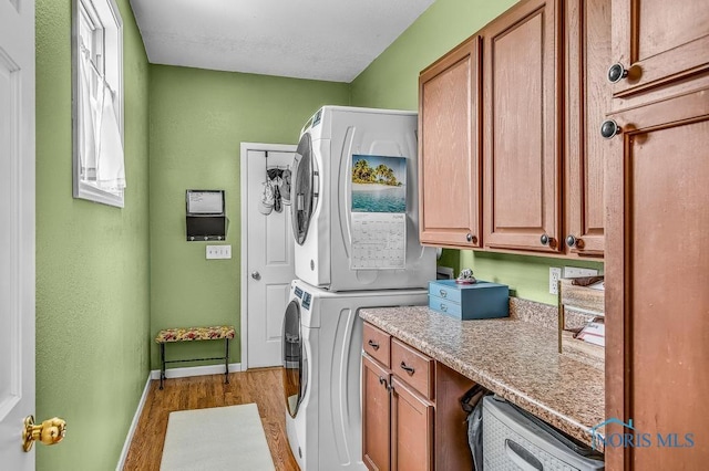 5872 Settlers Ridge Cir, Sylvania, OH 43560 - washroom featuring estacked washer and dryer, cabinet space, and light wood-style flooring