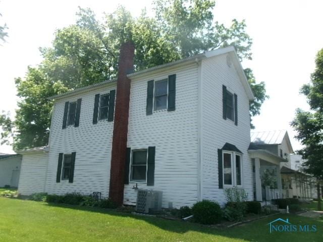 252 N Walnut St, Ottawa, OH 45875 - view of side of home featuring a lawn and a chimney