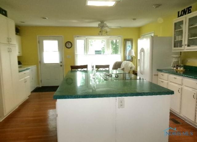 252 N Walnut St, Ottawa, OH 45875 - kitchen with black electric cooktop, dark countertops, a kitchen island, white cabinets, and dark wood-style floors
