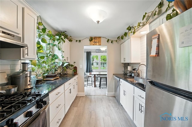 1022 Clough St, Bowling Green, OH 43402 - kitchen with appliances with stainless steel finishes, ventilation hood, decorative backsplash, light wood finished floors, and white cabinetry