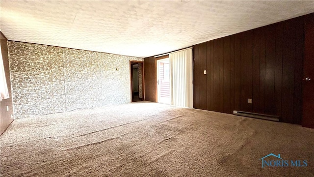 825 Johnson Rd, Paulding, OH 45879 - carpeted empty room featuring a baseboard radiator, a textured ceiling, and wooden walls
