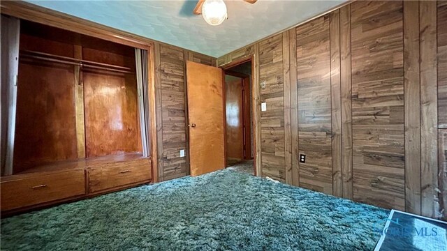 825 Johnson Rd, Paulding, OH 45879 - unfurnished bedroom featuring wood walls, a closet, and carpet