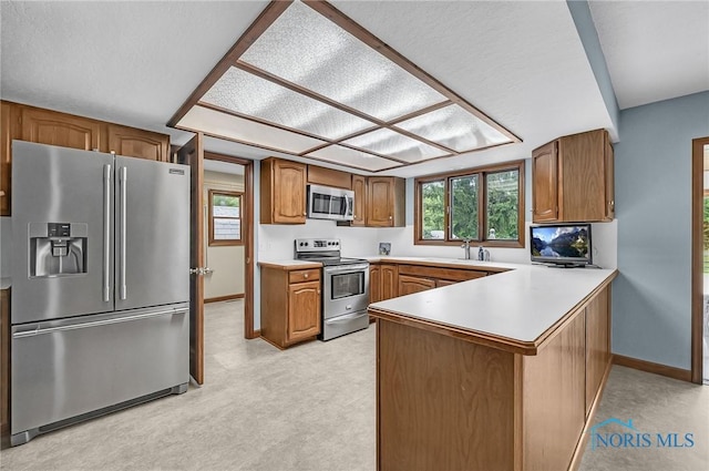 7040 Country Creek Rd, Maumee, OH 43537 - kitchen featuring stainless steel appliances, a peninsula, brown cabinets, and light countertops