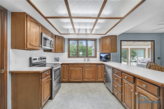 7040 Country Creek Rd, Maumee, OH 43537 - kitchen with appliances with stainless steel finishes, light countertops, brown cabinetry, and a peninsula