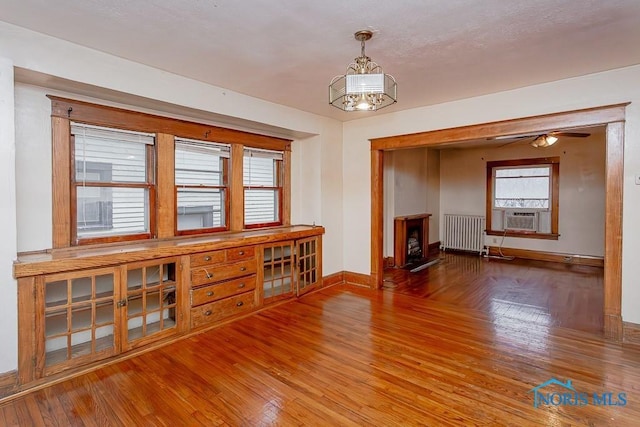 433 Islington St, Toledo, OH 43610 - unfurnished living room featuring radiator, wood finished floors, cooling unit, and a chandelier