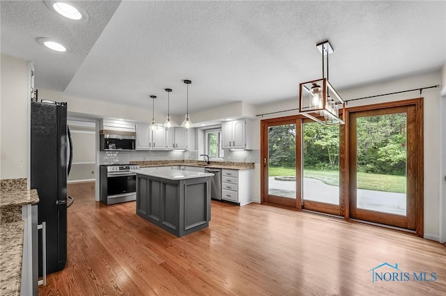 1626 Woodstream Rd, Perrysburg, OH 43551 - kitchen with stainless steel appliances, a textured ceiling, light wood-style floors, backsplash, and a kitchen island