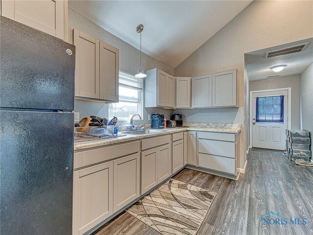 5161 Langham Dr, Sylvania, OH 43560 - kitchen featuring freestanding refrigerator, vaulted ceiling, light countertops, light wood-type flooring, and decorative light fixtures