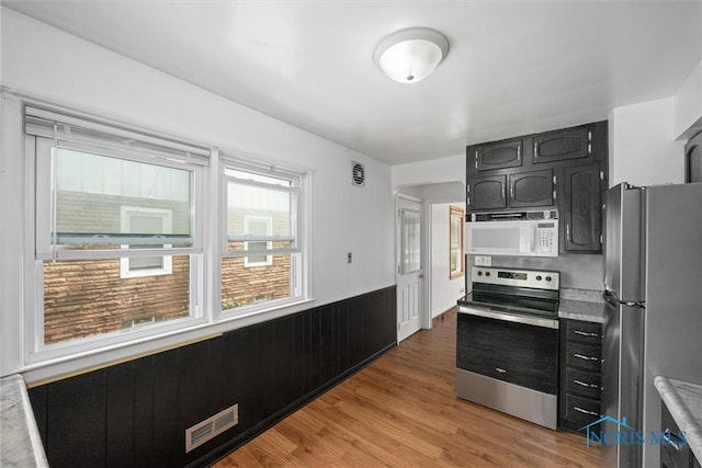 42 California Blvd, Toledo, OH 43612 - kitchen with stainless steel appliances, wainscoting, light countertops, light wood finished floors, and dark cabinetry