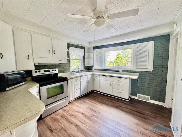 908 E High St, Hicksville, OH 43526 - kitchen with stainless steel appliances, light countertops, white cabinets, ornamental molding, and brick wall