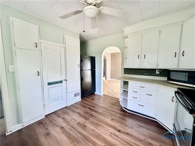 908 E High St, Hicksville, OH 43526 - kitchen featuring range, stainless steel microwave, freestanding refrigerator, crown molding, and white cabinetry