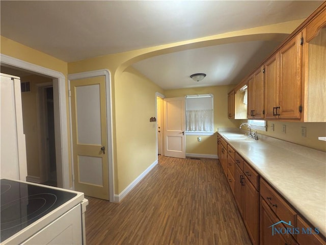 1007 Leonard Ct, Fostoria, OH 44830 - kitchen with white range with electric stovetop, dark wood finished floors, arched walkways, light countertops, and brown cabinetry