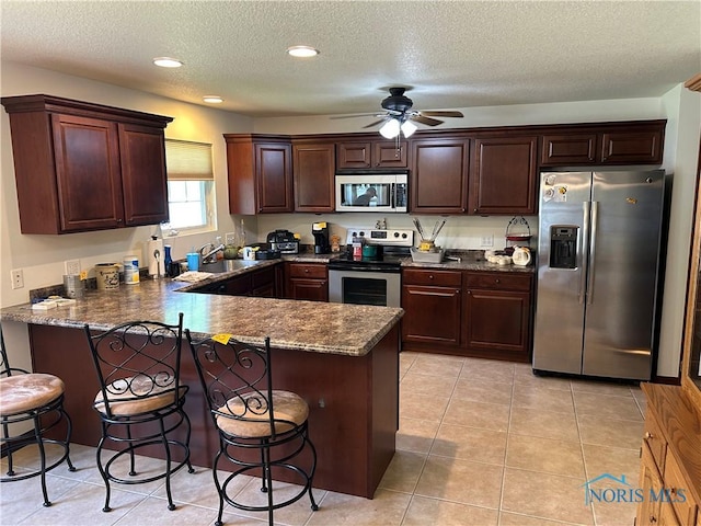 2440 Bluestone Dr, Findlay, OH 45840 - kitchen featuring stainless steel appliances, a peninsula, a ceiling fan, a breakfast bar, and a textured ceiling