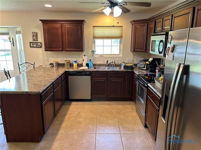 2440 Bluestone Dr, Findlay, OH 45840 - kitchen featuring appliances with stainless steel finishes, dark countertops, a peninsula, a ceiling fan, and dark brown cabinets