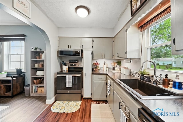 634 Cherry St, Findlay, OH 45840 - kitchen with appliances with stainless steel finishes, a textured ceiling, light wood-style floors, arched walkways, and dark countertops