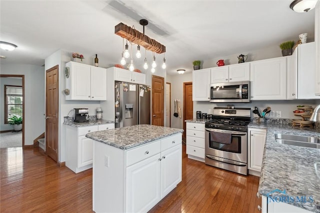 2393 Woods Edge Rd, Perrysburg, OH 43551 - kitchen with appliances with stainless steel finishes, hardwood / wood-style floors, a kitchen island, white cabinets, and light stone countertops